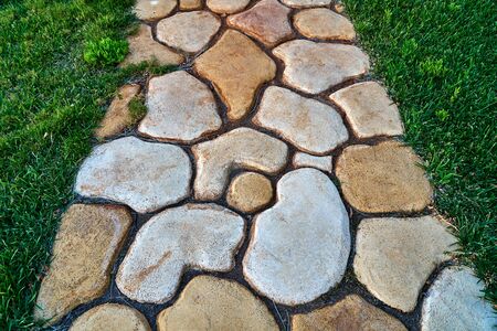 Sidewalk tiles of different shapes and colors on the grassの写真素材