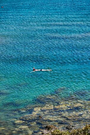 Lonely swimmer in a mask floating near the shoreの写真素材