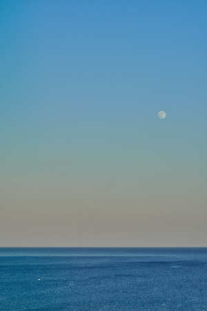 Moon over the calm sea on a warm eveningの写真素材