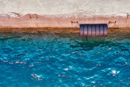 Concrete sea pier with hanging old tiresの写真素材
