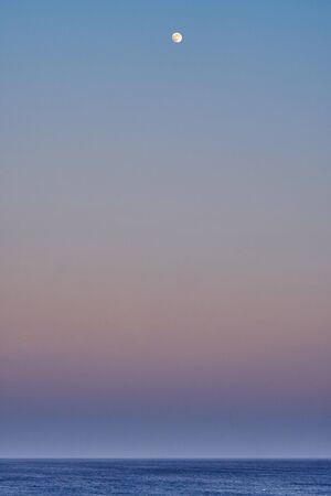 Moon over the calm sea on a warm eveningの写真素材