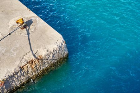 Sea concrete pier with a yellow bollardの写真素材