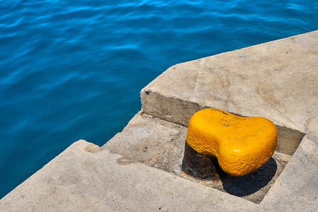 Yellow mooring bollard on a concrete sea pierの写真素材