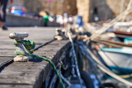 Metal mooring bollard on a wooden pier with moored yachtsの写真素材