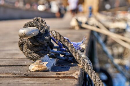 Metal mooring bollard on a wooden pier with moored yachtsの写真素材