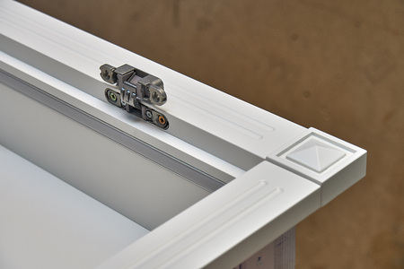 White cabinet with hidden hinges and shelf holders. Close-up. Wooden furniture manufacturing process
