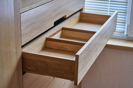 Interior wooden cupboard with empty shelves and opened drawer in daylight. Modern furnitureの写真素材