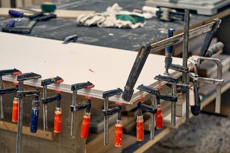 Gluing and clamping table top of acrylic stone in workshop. Furniture manufacture. Close-upの写真素材