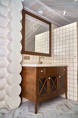 Elegant bathroom vanity cabinet with acrylic countertop and wood mirror frame located near tiled wall inside luxury water closet. Country style. Details furnitureの写真素材