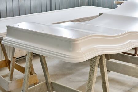 Curved crown molding of a classic wardrobe after finishing painting in painting chamber. Furniture...