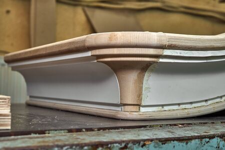 Curved crown molding of a classic wardrobe in process of production in workshop. Furniture...