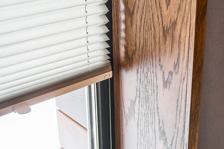 Oak veneer window slopes. Wooden slopes on the window. Window with pleated shades. Close-upの写真素材