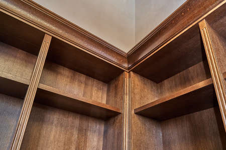 Home library. Detail of antique wooden bookcase with empty shelves placed in home library in houseの写真素材