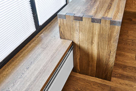 Modern furniture. Box joint solid wooden console desk against the background of the windowの写真素材