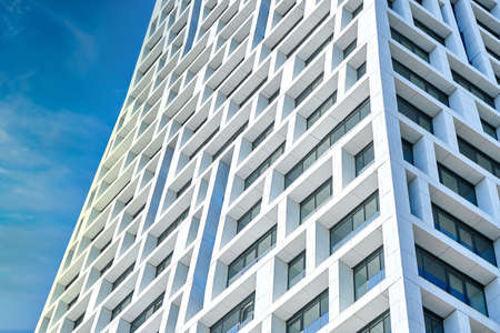 Contemporary high rise urban building with geometric design against cloudy blue sky in sunny day in cityの写真素材