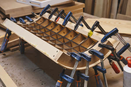 Joinery. Plywood bending process close-up. Gluing and clamping bend wooden panel. Bend furniture manufactureの写真素材