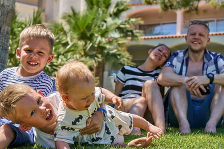 Happy family. Happy boys smiling and playing together on grass near father and mother on summer day