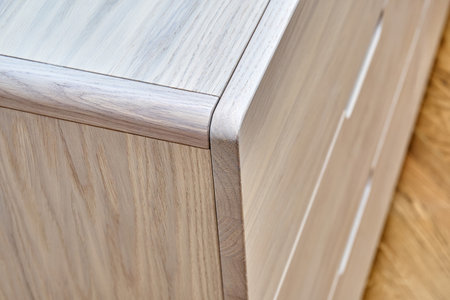 Stylish chest of drawers made with bleached solid oak with finger pull sliders stands on floor in...