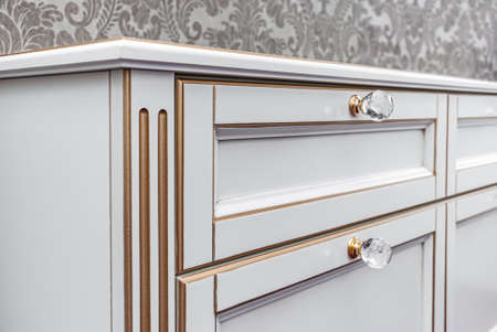 Classical bedside table with drawers and crystal handles on floral wallpaper background, closeupの写真素材