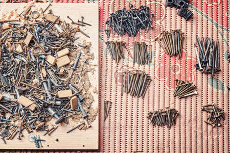 Woodwork garbage of shavings anchors and nails and sorted different self-tapping screws on colorful...