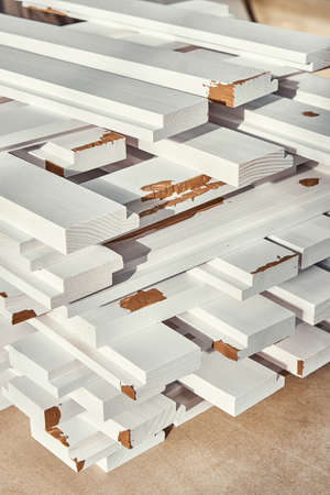 Stack of wooden bars of solid pine in white color with brown putty lie on workbench closeup