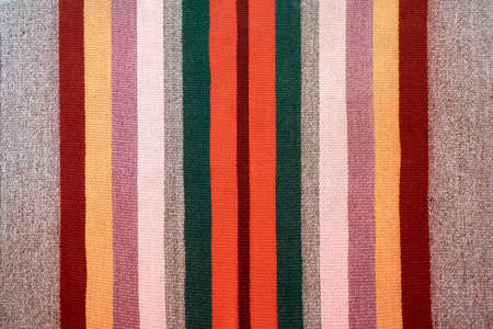 Stylish gray ethnic traditional handmade carpet decorated with different colorful stripes on floor...