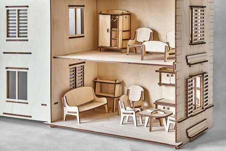 Cute doll house with toy furniture made of plywood details cut with laser machine tool stands with open wall on light gray closeupの写真素材
