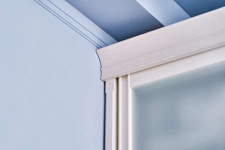 Stylish wardrobe top with matte glass on sliding doors standing near blue wall closeupの写真素材