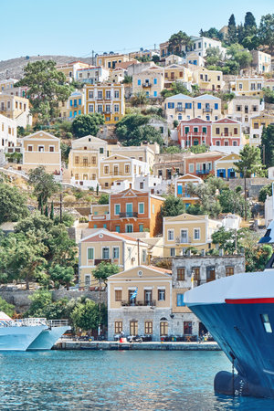 Moored large yacht on sea against historical town with old multicolored buildings scattered on hills...