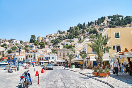 Symi, Greece - July 05 2017: Multicolored historical buildings in old town scattered on hills on Symi island on sunny day in Greeceのeditorial素材