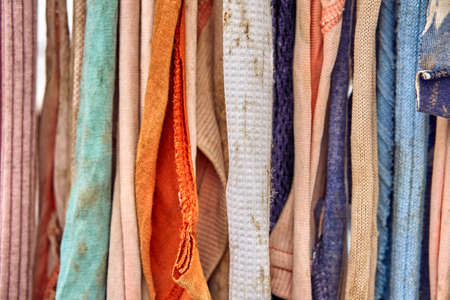 Colorful pieces of old dirty rags hang on a rope as a striped background extreme closeup viewの写真素材