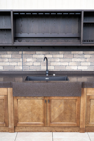 Comfortable modern summer kitchen with furniture made of veneer and solid ash with acrylic solid surface countertop and new sink on terrace at country houseの写真素材