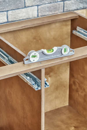 Detail of kitchen furniture made of plywood and solid ash wood installed according to level near...