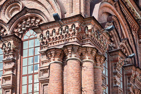 Wonderful historical building with red brick walls columns and high arch windows on city street in old downtown on sunny dayの写真素材