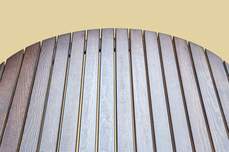 Round table top made of wooden slats for outdoor table isolated on beige background close upper view