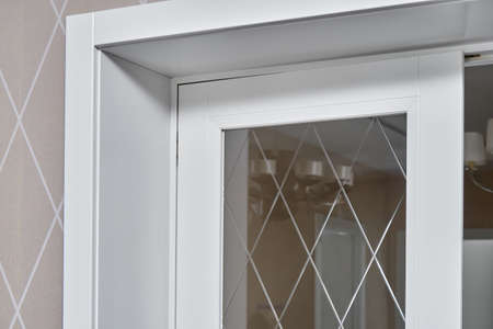 Elegant trendy inner doors with rhombus pattern on glass surface and silver handles in light spacious room of renovated apartment closeupの写真素材