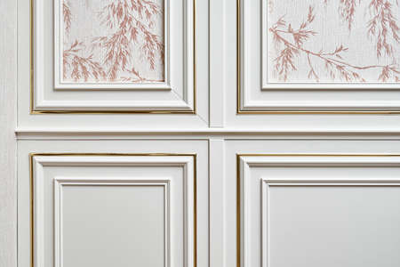White wall panel with gold molding in classic style with wallpaper with floral pattern in light spacious room of cottage closeupの写真素材