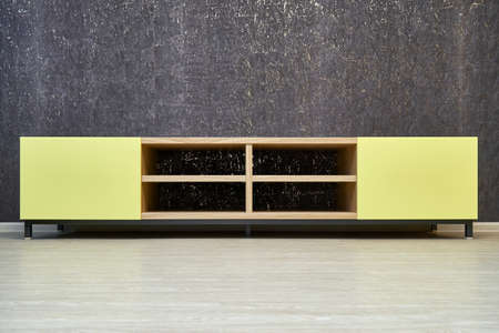 Elegant empty TV stand made of oak wood veneer with bright yellow facade in minimal style near dark cork wall in light living roomの写真素材