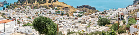 Lindos, Greece - July 08 2017: Ancient Lindos city on Rhodes island with white houses and private green gardens scattered on sea bay coast with turquoise waterのeditorial素材