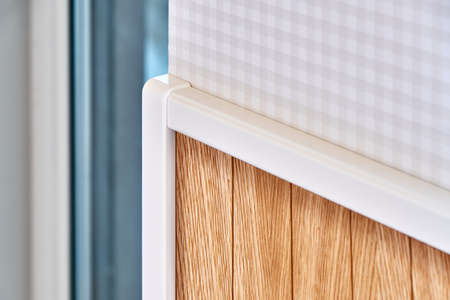Stylish contemporary wainscoting made of thin light toned oak timber planks with white molding near window close viewの写真素材