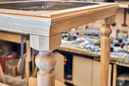 Wooden dining table with carved leg of solid oak and metal frame build process in workshop close up viewの写真素材