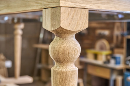 Wooden dining table with carved leg of solid oak and metal frame build process in workshop extreme closeup viewの写真素材