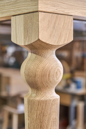 Wooden dining table with carved leg of solid oak and metal frame build process in workshop extreme closeup viewの写真素材