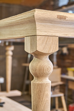 Wooden dining table with carved leg of solid oak and metal frame build process in workshop extreme closeup viewの写真素材