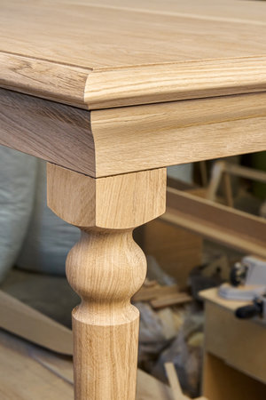 Wooden dining table with carved leg of solid oak and metal frame build process in workshop close up viewの写真素材