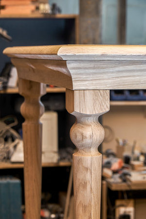 Wooden dining table with carved leg of solid oak and metal frame build process in workshop close up viewの写真素材