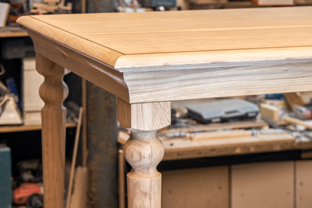 Wooden dining table with carved leg of solid oak and metal frame build process in workshop close up viewの写真素材