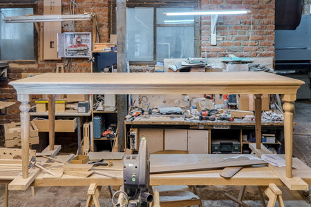 Wooden dining table with carved leg of solid oak and metal frame build process in workshopの写真素材