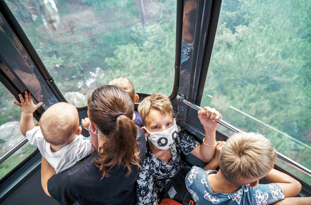 Mother with children ride funicular standing in cabin over green park. Large family with kids enjoy cable road trip together. Roperoad ridingの写真素材