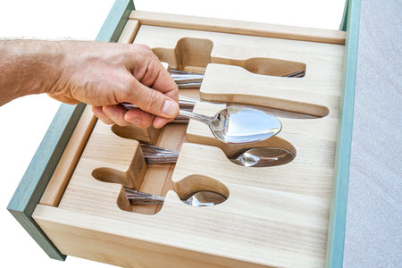 Man hand puts spoon in craved wooden holder in kitchen cabinet drawer closeup. Person takes cutlery from storage tray. Home furnitureの写真素材
